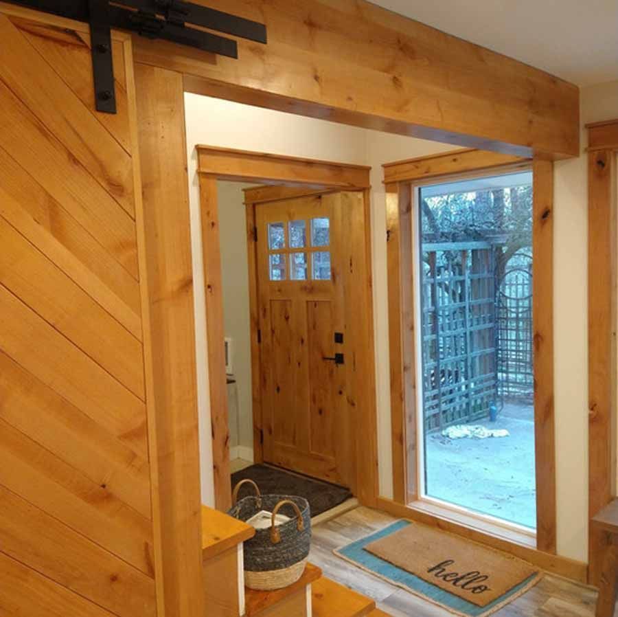 A hallway with a sliding barn door and a door mat that says hello