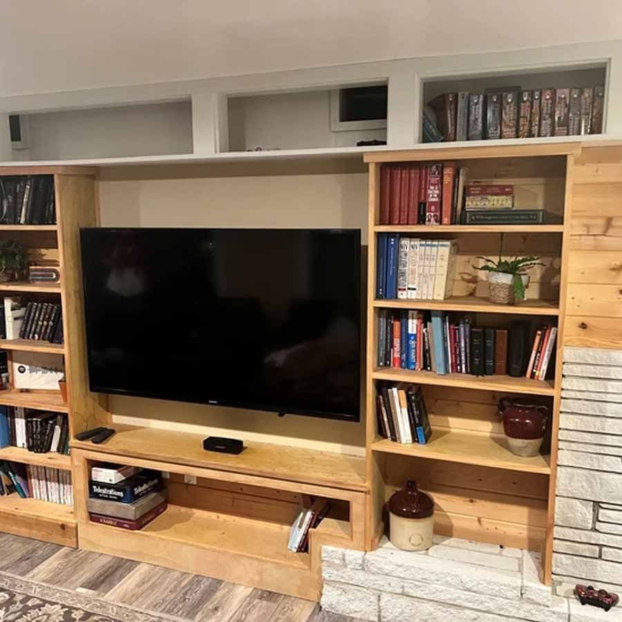 A living room with a fireplace , bookshelves , and a flat screen tv.
