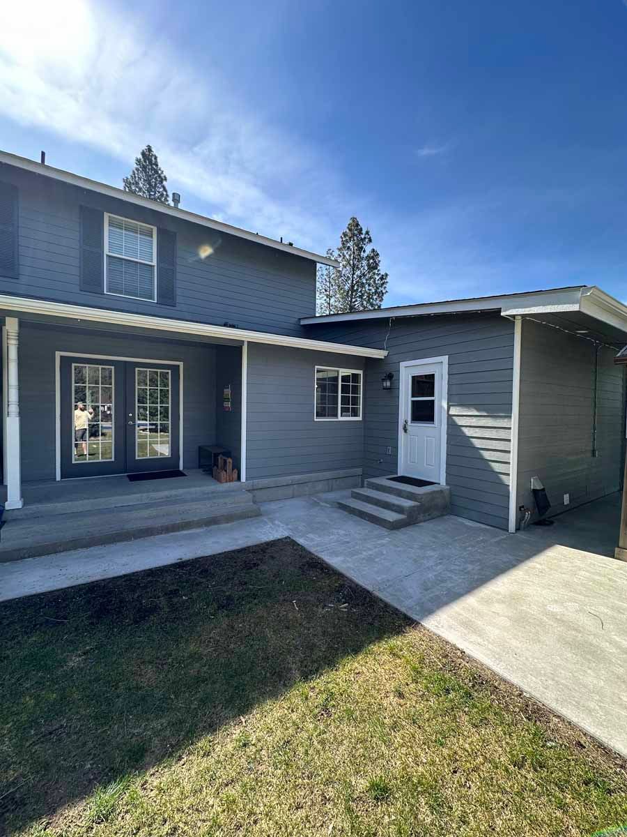 A gray house with a covered porch and a white door.