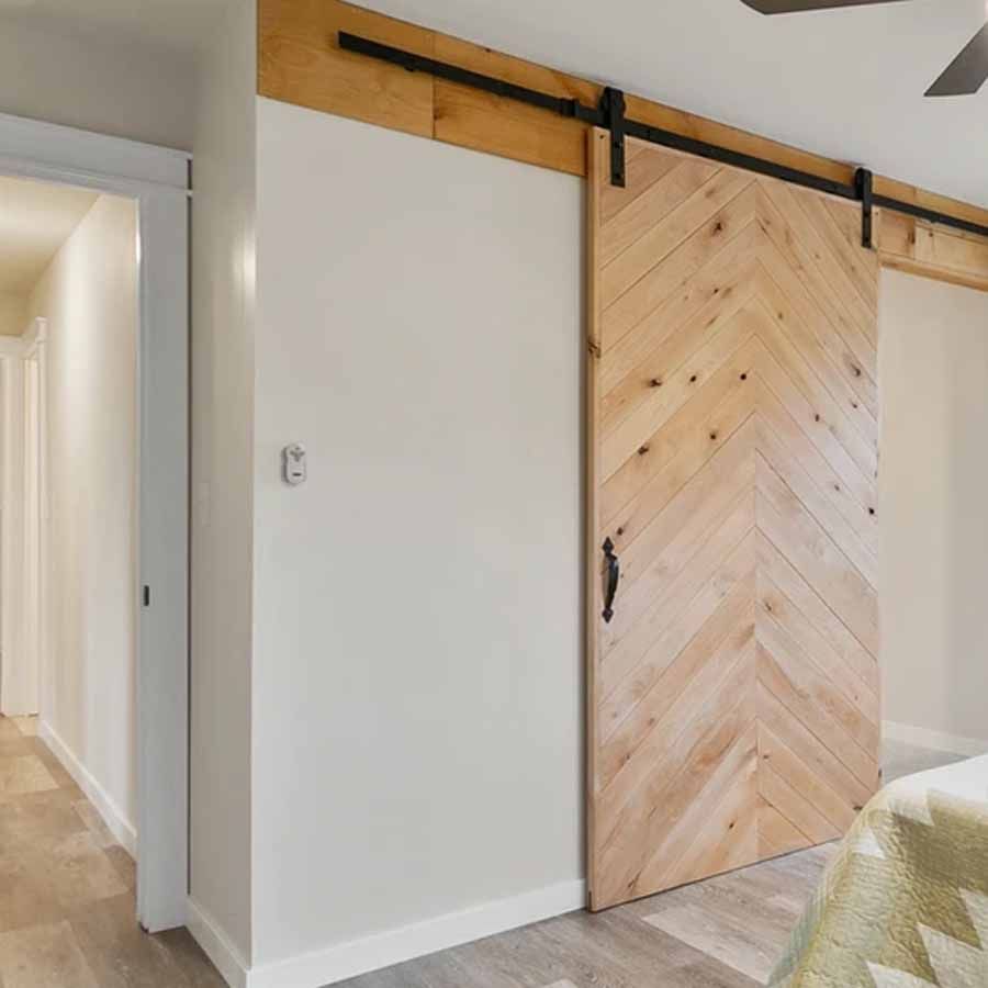 A bedroom with a sliding barn door and a ceiling fan.