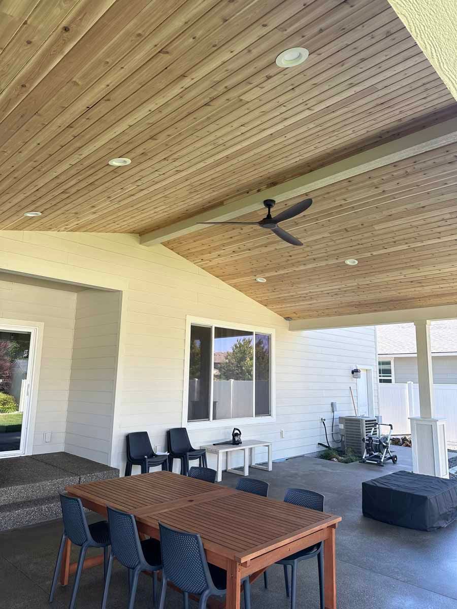 A patio with a table and chairs and a ceiling fan.
