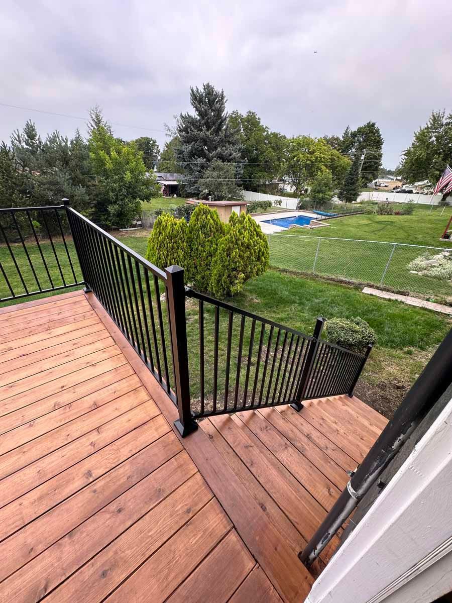 A wooden deck with a metal railing and stairs leading up to it.