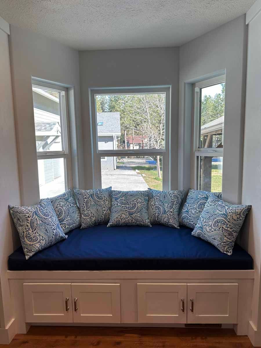 A window seat with blue cushions and pillows in a living room.