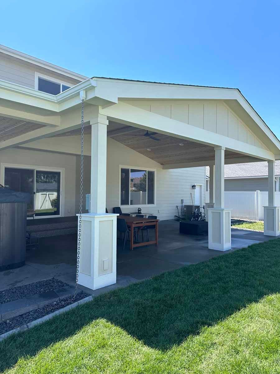 A house with a covered patio and a hot tub in the backyard.