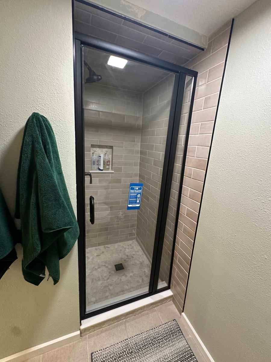 A bathroom with a walk in shower and towels hanging on the wall.