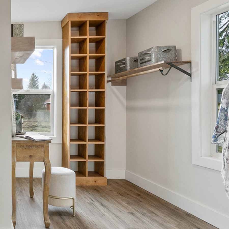A walk in closet with a wooden shelf and a window.