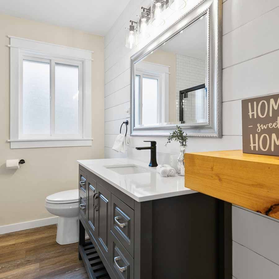 A bathroom with a sink , toilet , mirror and a sign that says home sweet home.