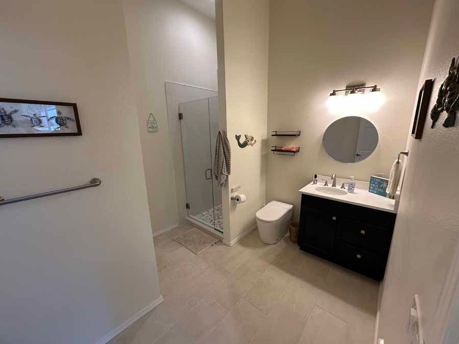 A bathroom with a toilet , sink , mirror and walk in shower.