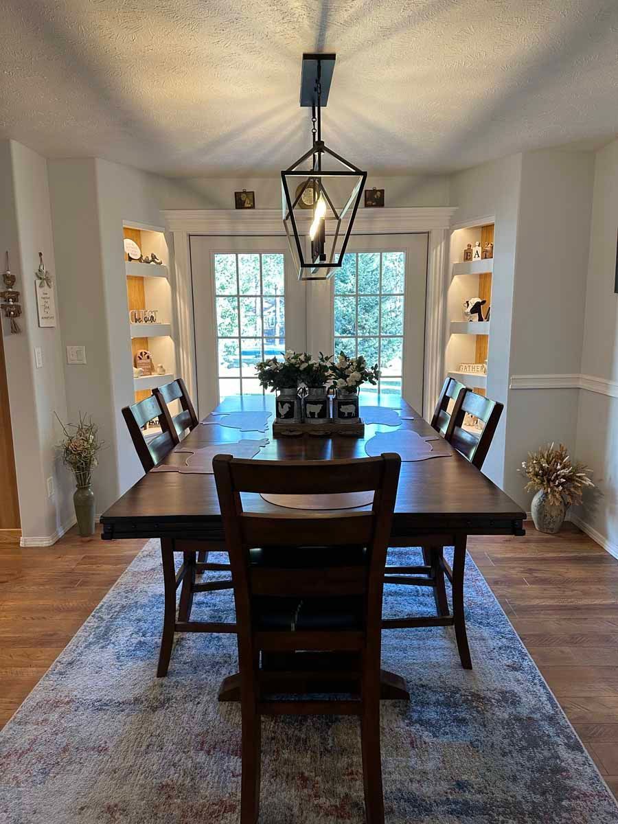 A dining room with a table and chairs and a rug.