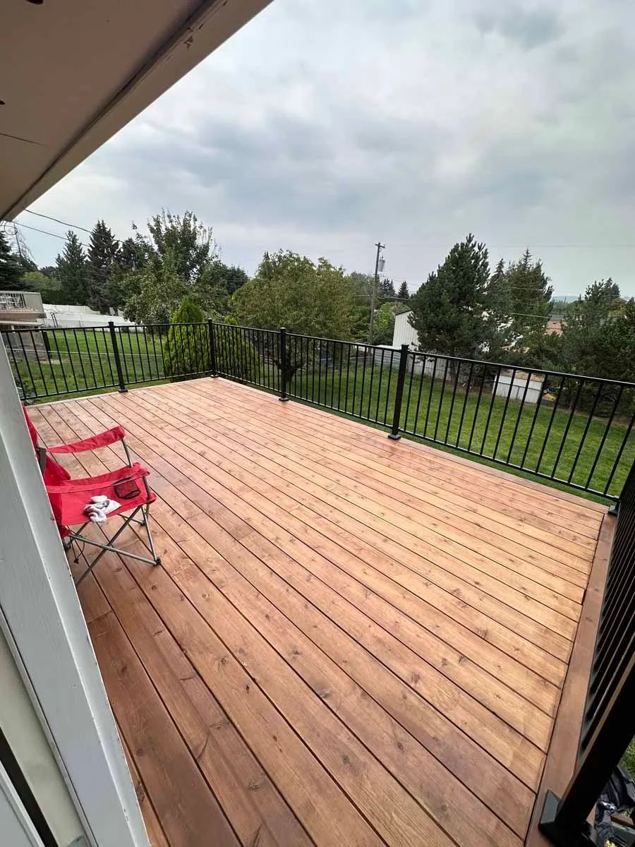 A wooden deck with a chair on it and a fence.