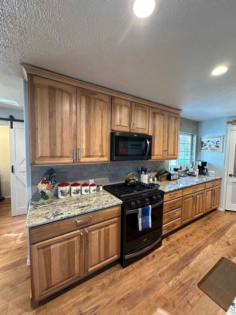 A kitchen with wooden cabinets , granite counter tops , a stove and a microwave.