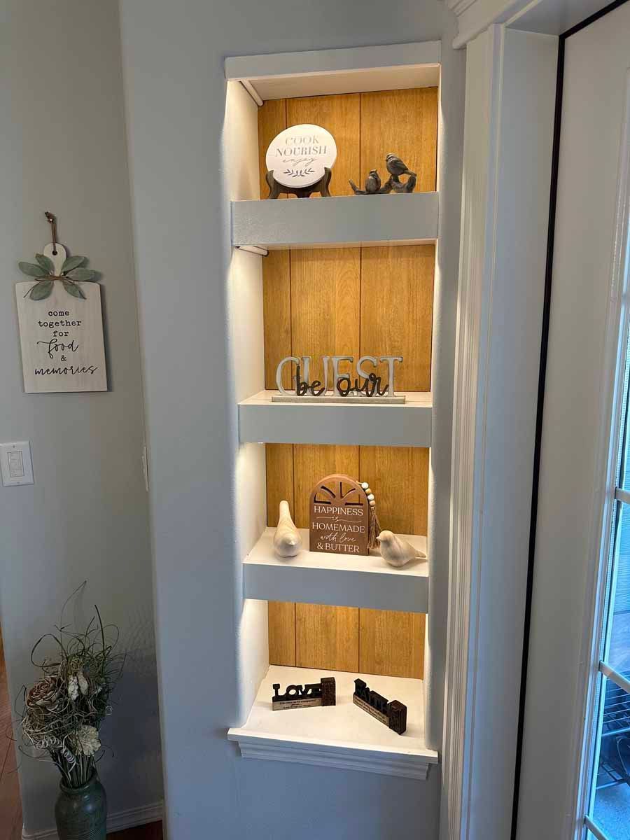 A shelf with a vase of flowers on it in a room next to a door.