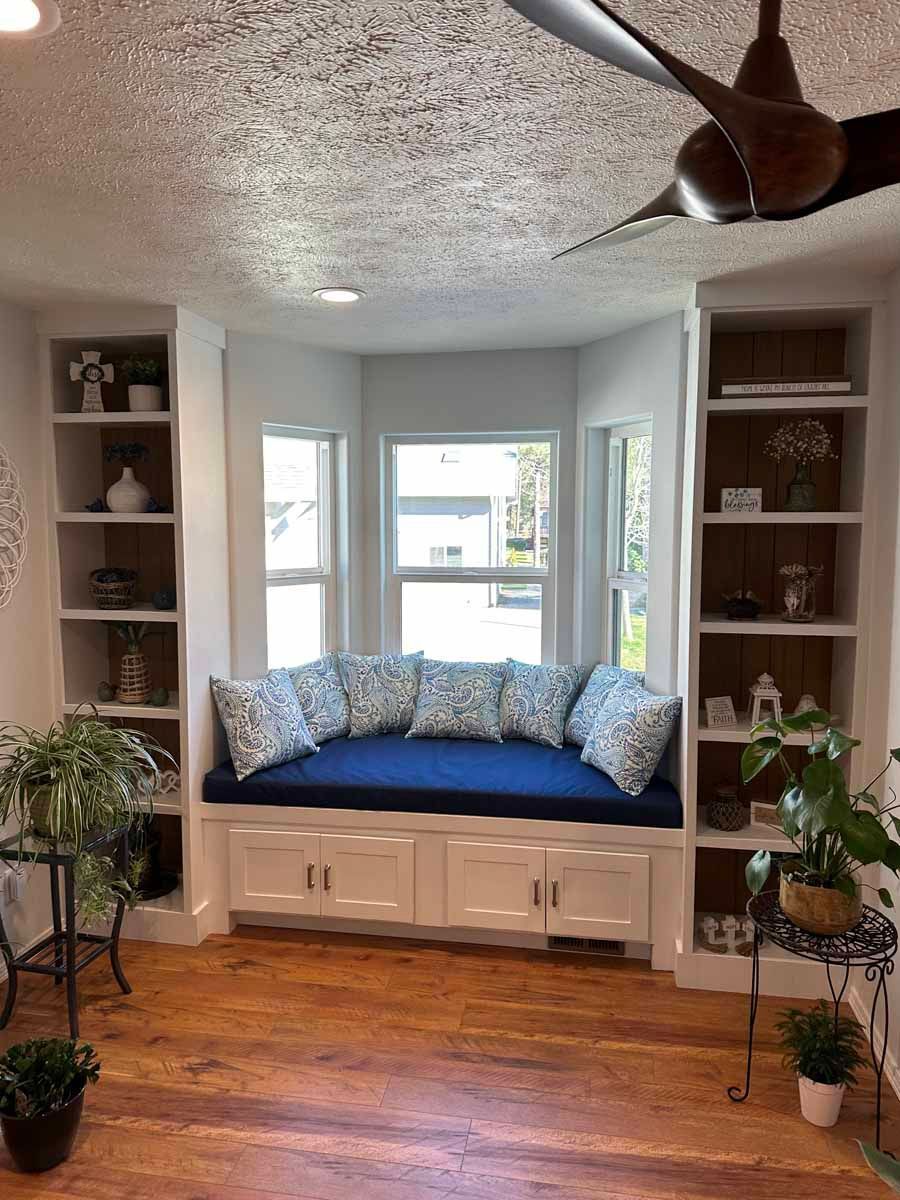 A living room with a window seat and a ceiling fan.
