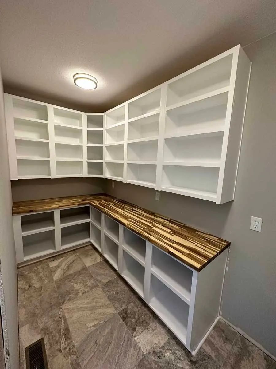 A room with a lot of shelves and a wooden counter top.