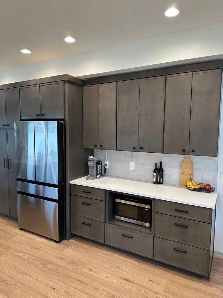 A kitchen with stainless steel appliances and gray cabinets.