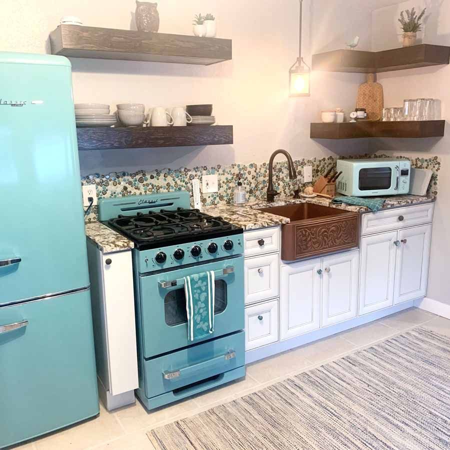 A kitchen with a stove , refrigerator , sink and microwave.