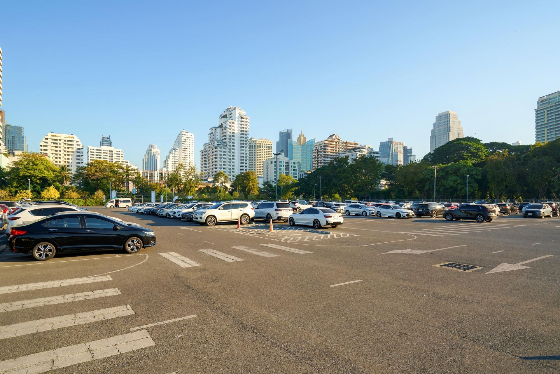 A lot of cars are parked in a parking lot with a city in the background. A lot of cars are parked in a parking lot with a city in the background.