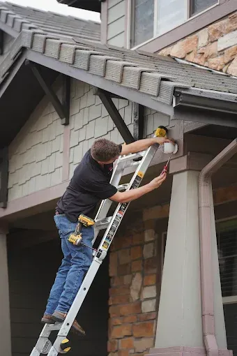White doorbell camera on a brown door, near a black doorknob and lock.