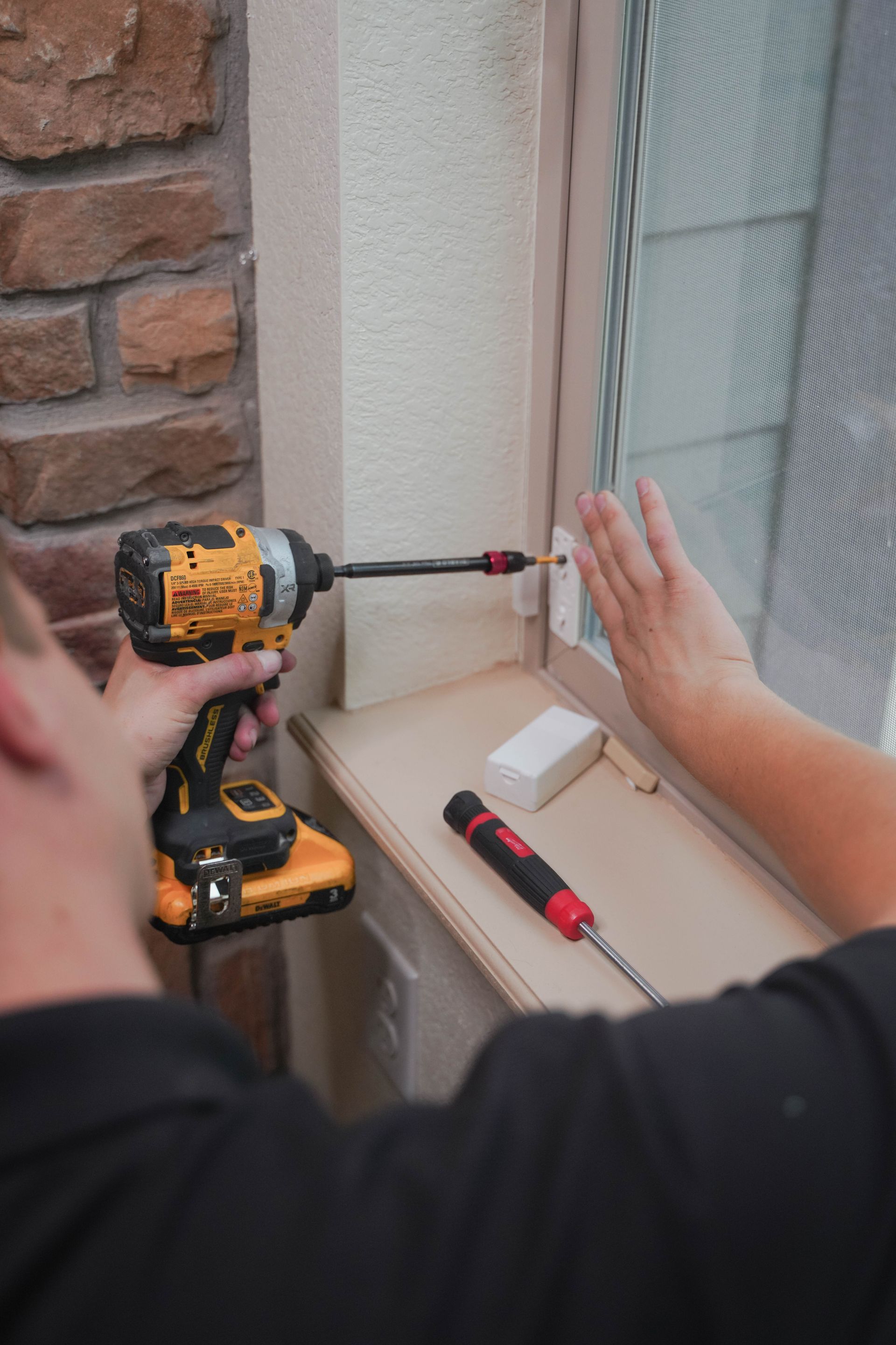 White doorbell camera on a brown door, near a black doorknob and lock.