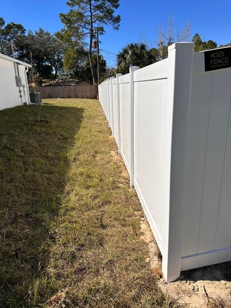 A white vinyl fence is sitting in the middle of a grassy yard.