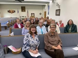Group seated in a church hall, facing the camera and smiling.