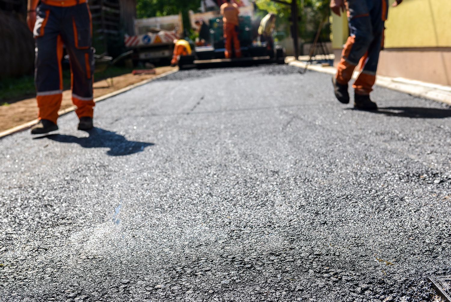 A road work crew is paving a surface, showcasing a driveway paving contractor in action. A road work crew is paving a surface, showcasing a driveway paving contractor in action.