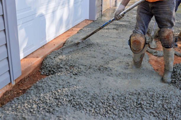 Paving contractors pouring wet concrete while paving a driveway.