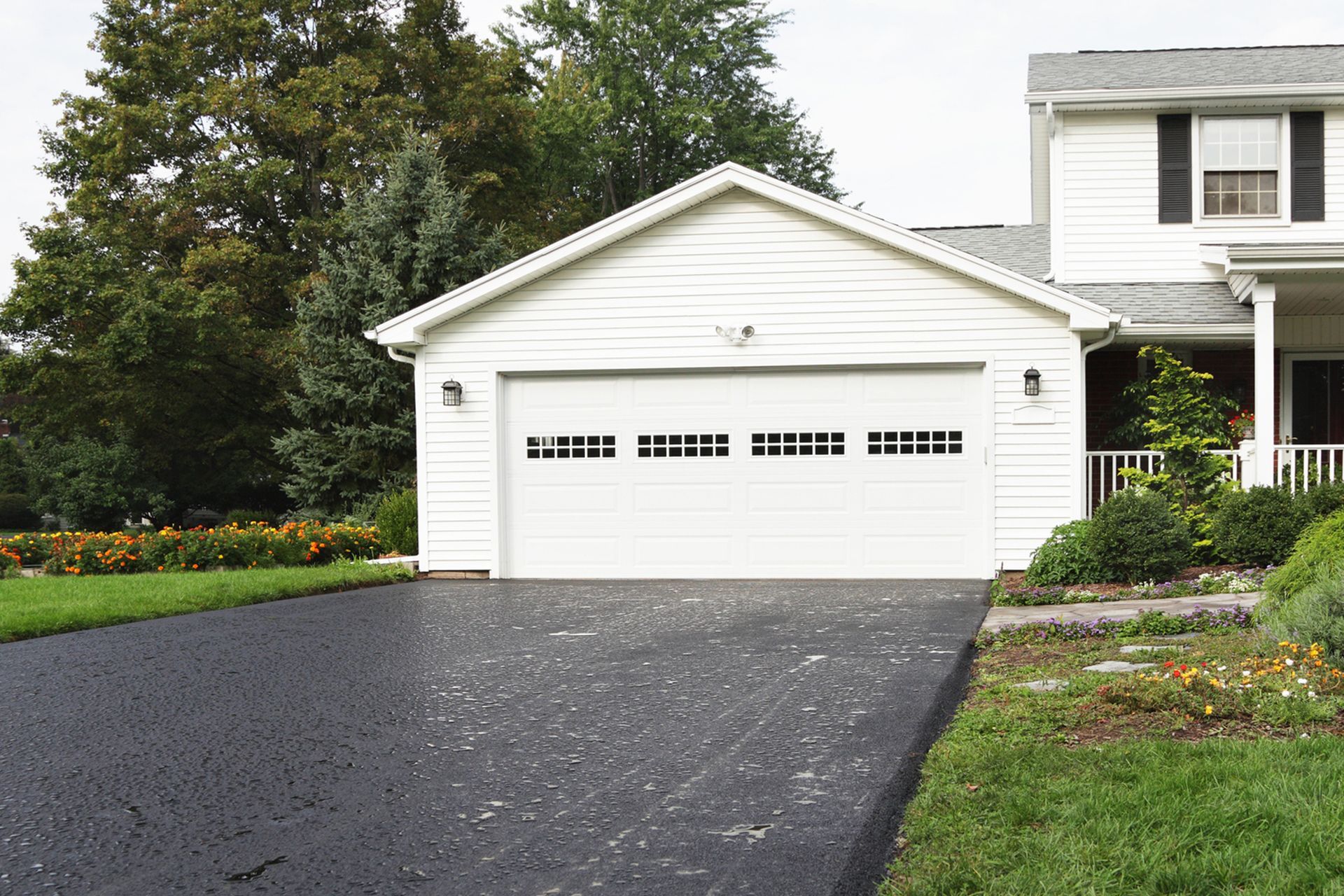A white house with a black driveway and a white garage door