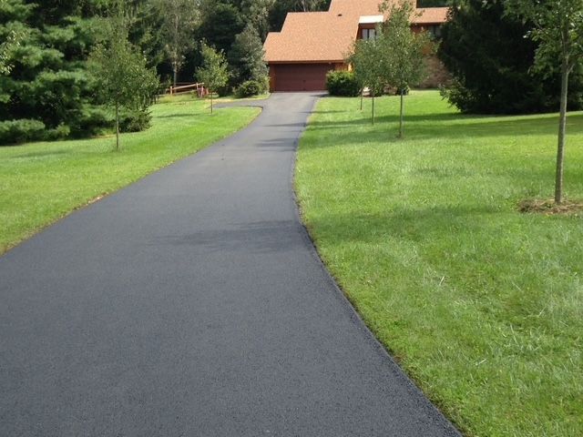 A driveway leading to a house surrounded by grass and trees