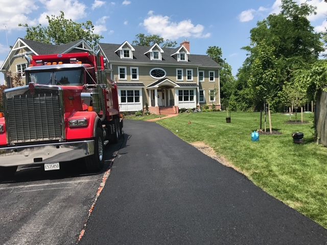 A red dump truck is parked in front of a large house