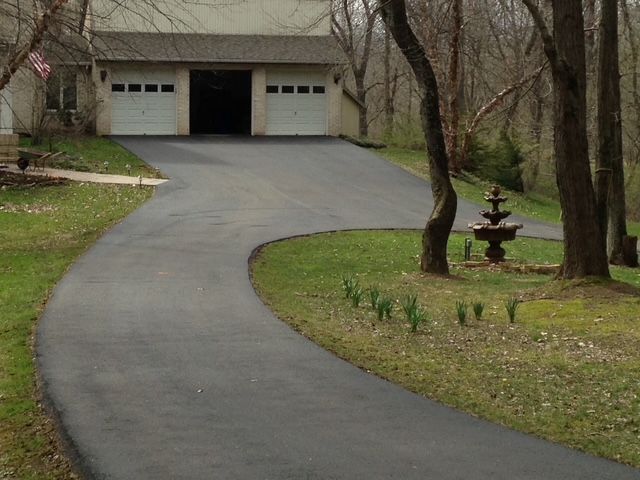 A driveway leading to a house with a fountain in the middle of it.
