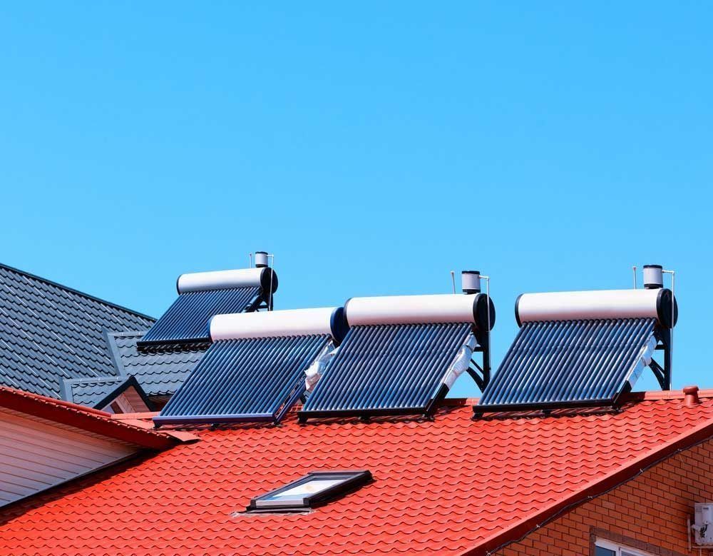 There are three solar panels on the roof of a house to help with a hot water system.