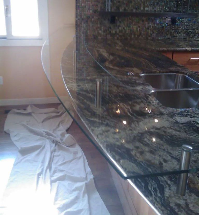 A kitchen counter with a curved glass top and two sinks