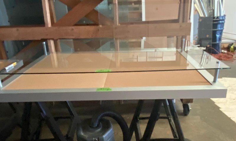 A table with a glass top and a vacuum cleaner on it.