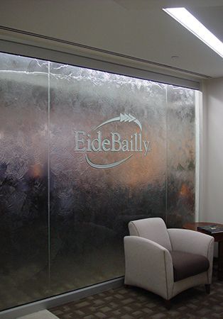 A chair is sitting in front of a glass wall with a logo on it.