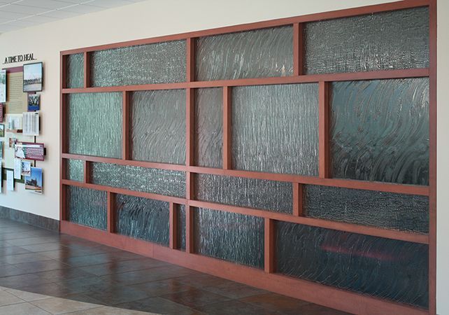 A hallway with a glass wall and a bulletin board