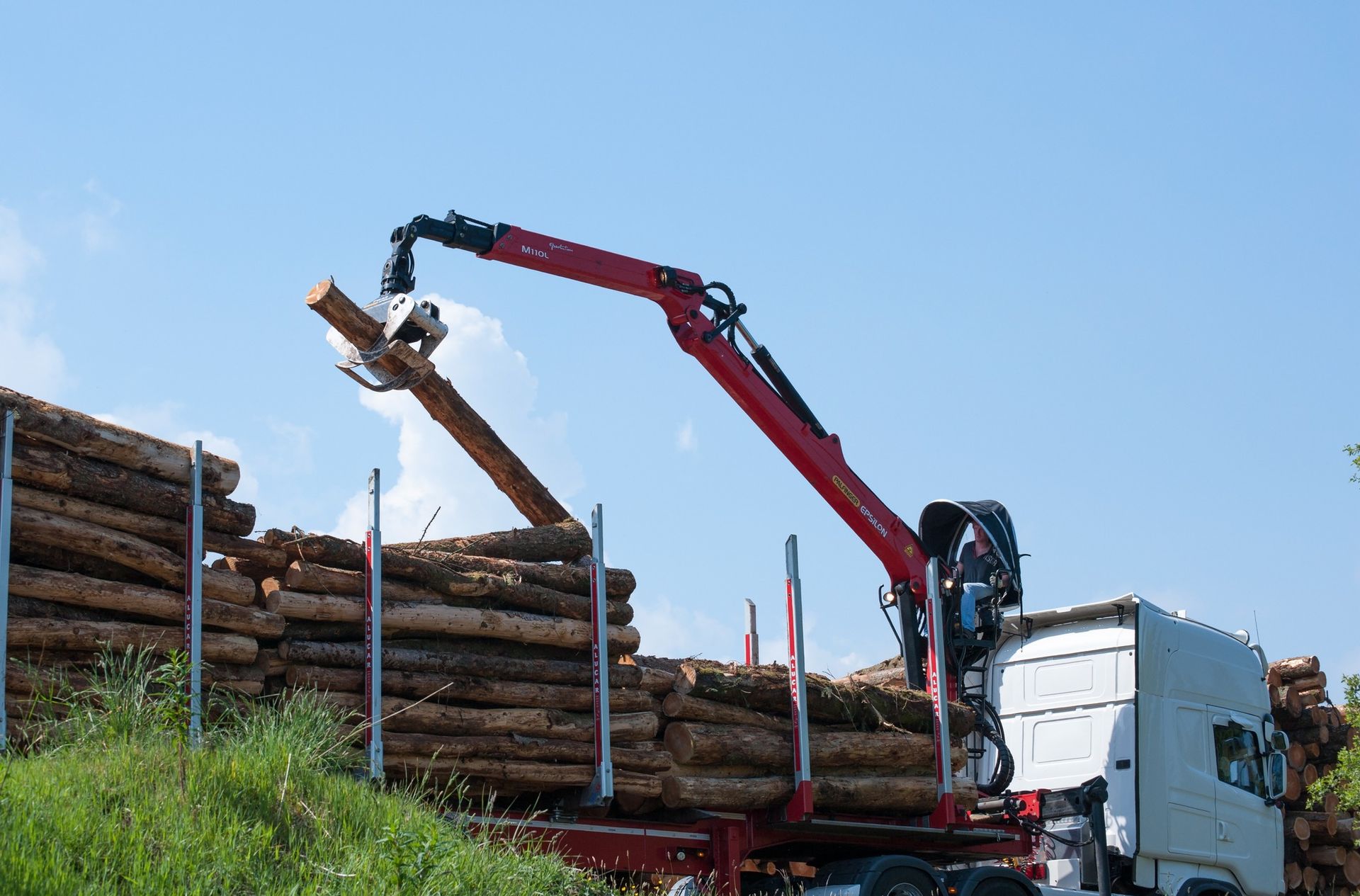 A crane is lifting a log from a truck.