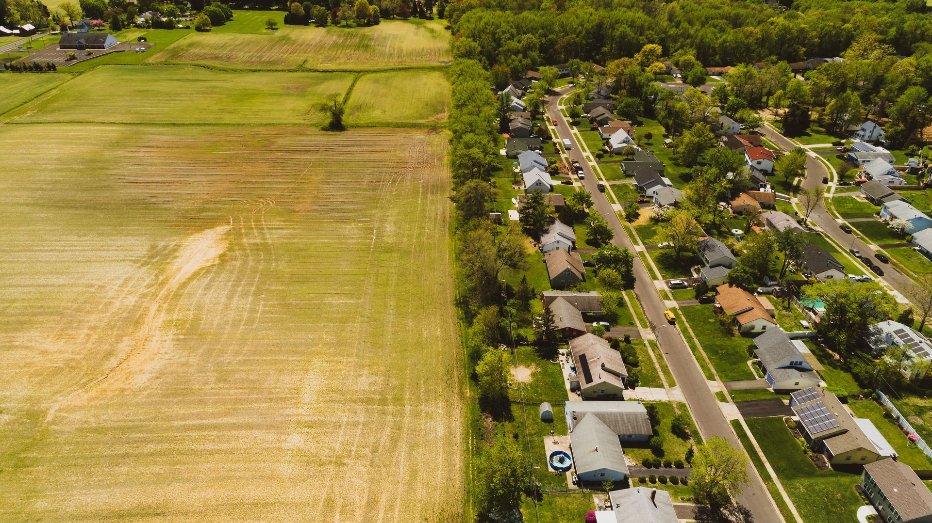An aerial view of a residential area with a field in the middle.