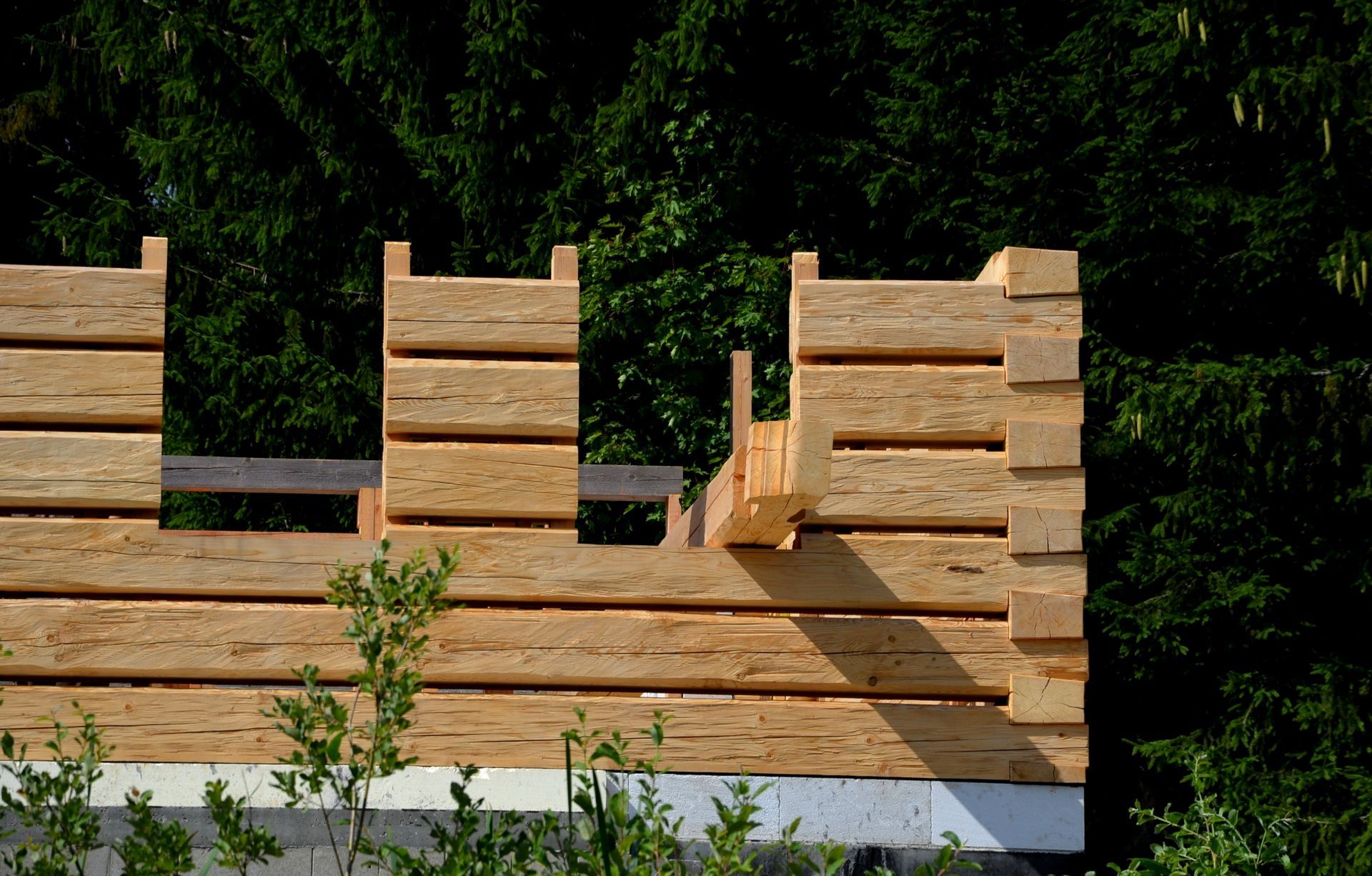 Construction of a wooden building wall with window frames. Forest background.