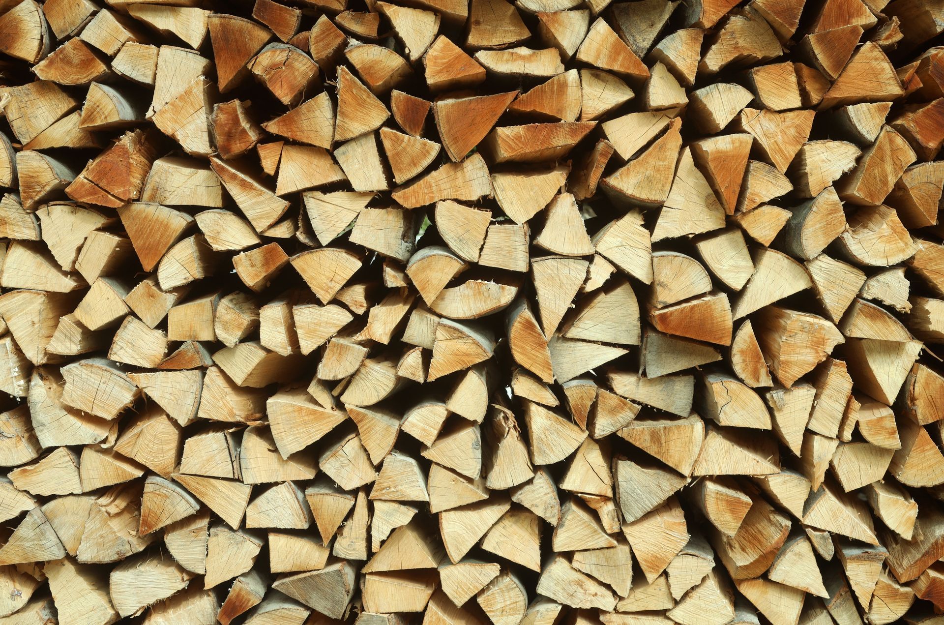 Pile of neatly stacked firewood, varying shades of brown.