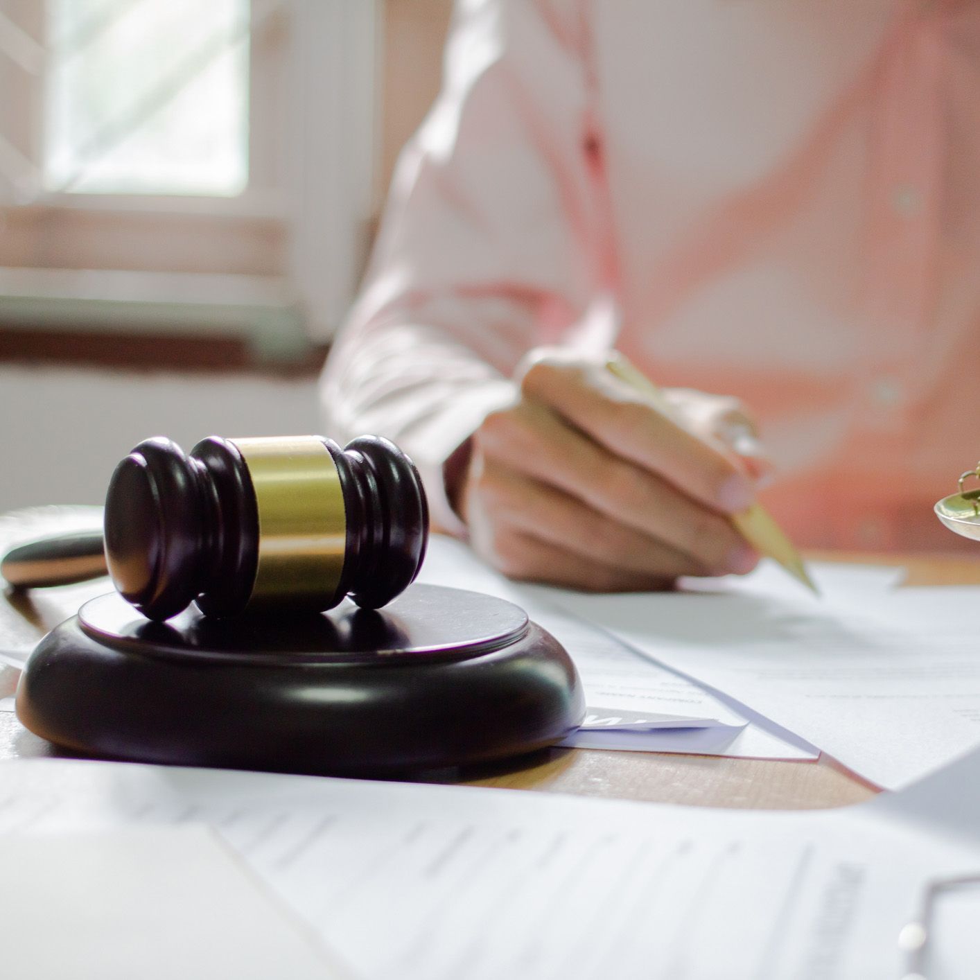 A person is writing on a piece of paper next to a judge 's gavel