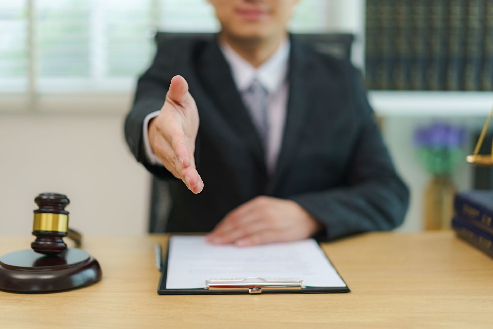 A lawyer is sitting at a desk with his hand outstretched.