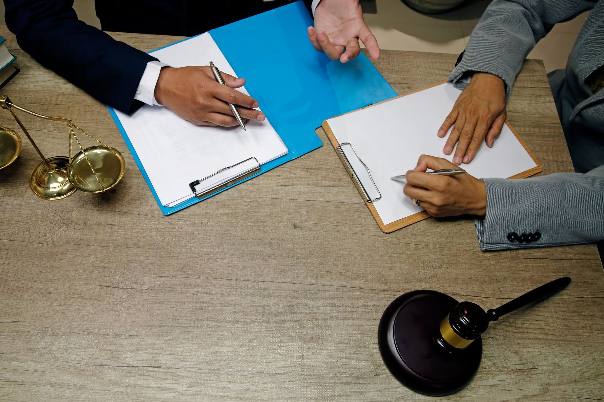 A man and a woman are sitting at a table with a clipboard and a judge 's gavel.