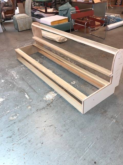A wooden shelf is sitting on a concrete floor in a room.