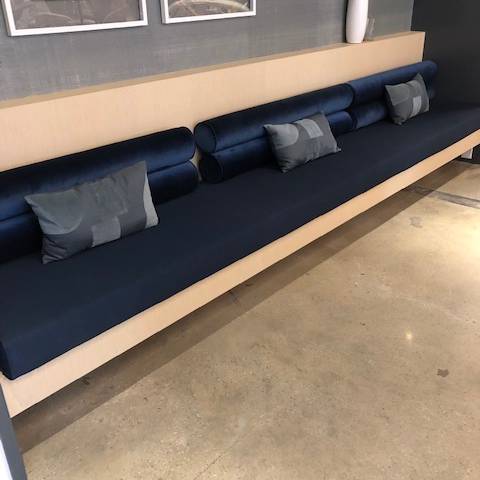 A long blue couch with pillows on it in a living room.