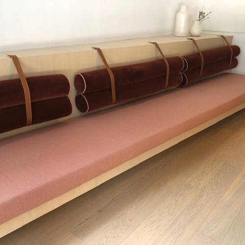 A couch with a pink cushion and brown pillows on it