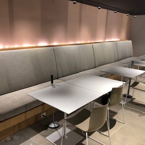 A restaurant with tables and chairs and a long bench.