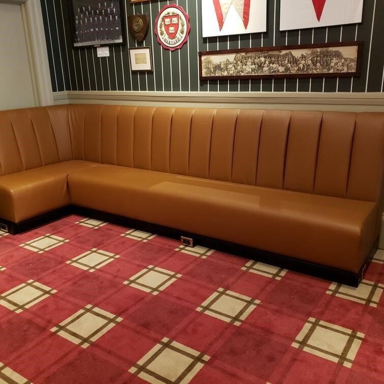 A long brown couch is sitting on a red rug