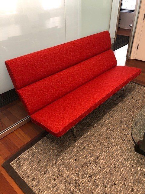 A red couch is sitting on a rug in a room