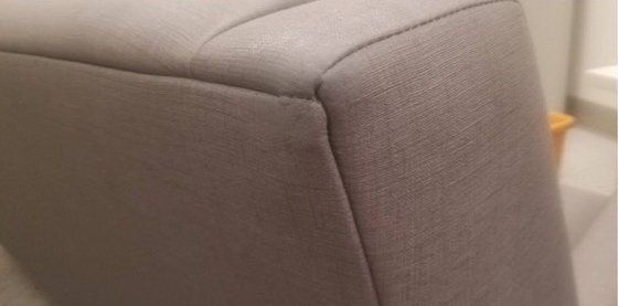 A close up of the corner of a grey couch.